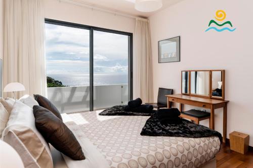 a bedroom with a bed and a desk and a window at OurMadeira - The Designhouse, contemporary in Arco da Calheta