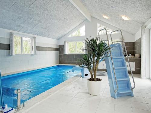 a large swimming pool with a blue pool slide in a room at 5 star holiday home in Nexø in Bedegård