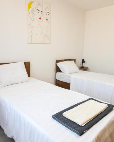 two beds with white sheets and a towel on them at Nuvelle Boutique Hotel in Prizren
