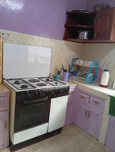 a kitchen with a black and white stove and purple cabinets at Rachel's Garden in Meru