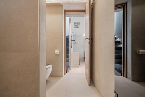 La salle de bains est pourvue de toilettes blanches et d'un couloir. dans l'établissement Hospi Living Stalida Beachfront Suites with Heated Jacuzzi, à Stalida