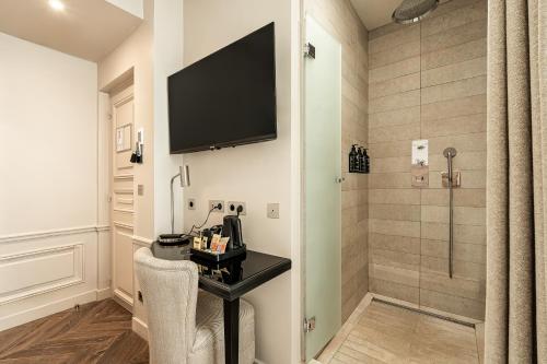 a bathroom with a desk and a shower with a television at Hôtel Perreyve - Jardin du Luxembourg in Paris
