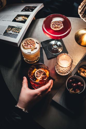 a person holding a drink on a table with a book at Excelsior Chamonix Hôtel & Spa in Chamonix-Mont-Blanc