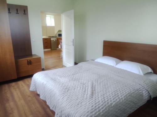 a bedroom with a white bed with a wooden headboard at Casa Corvinia in Hunedoara