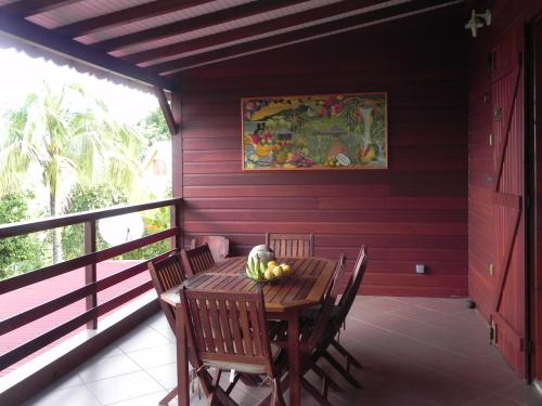 a wooden table with chairs and a bowl of fruit on a porch at Villa MIELéCAJOU, entre mer et montagne in Deshaies