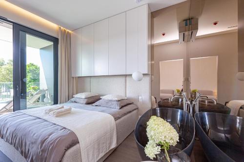 a bedroom with a bed and a table and chairs at Omega Lake Prestige # 5 Private Pool & Jacuzzi & Sauna & Gym & Lake Access in Olsztyn