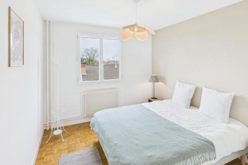 a white bedroom with a bed and a window at Le Balcon de Gallieni in Sainte-Savine