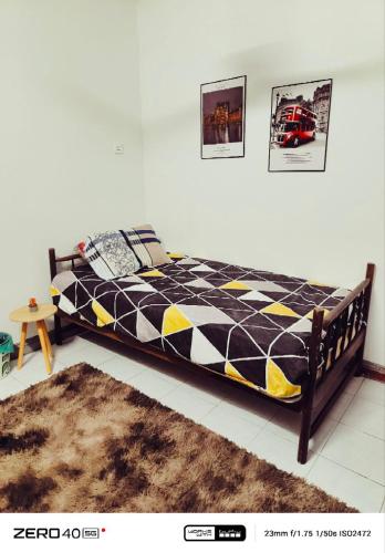 a bed with a black and yellow comforter in a room at Homestay D'Lapang near KLIA in Sepang