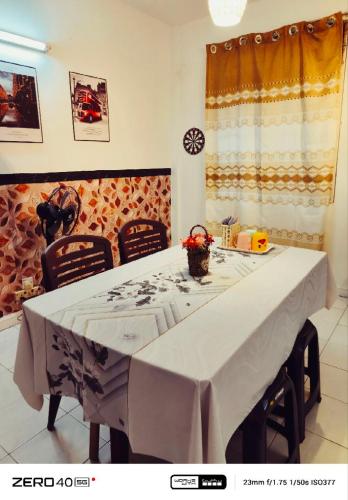a dining room table with a white table cloth and chairs at Homestay D'Lapang near KLIA in Sepang