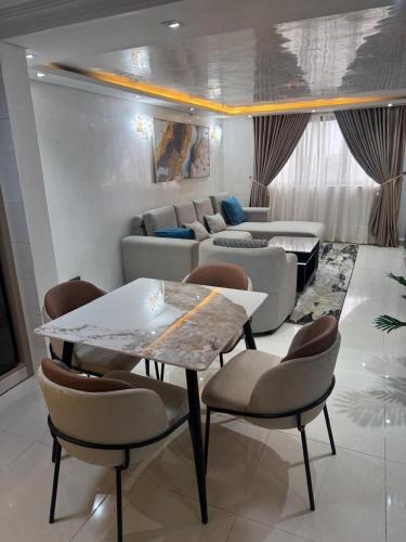 a living room with a table and chairs and a couch at Golden tulip apartment in Lagos