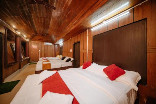 a room with three beds with red pillows on them at Munroe Island Lake Resort in Kollam