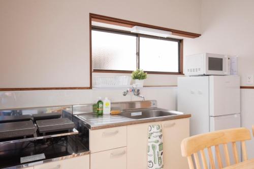 a small kitchen with a sink and a refrigerator at Kaze Box in Kasaoka