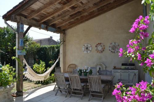 a patio with a table and chairs and flowers at Les volets bleus in Brie-sous-Mortagne