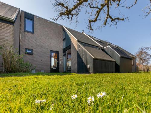 a house in a field with flowers in front of it at Holiday Home near Beach with Pool Access in Burgh Haamstede