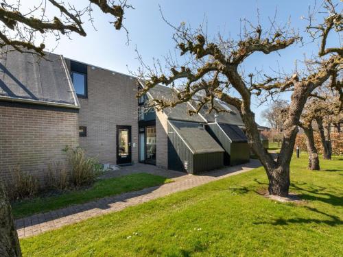 a brick house with a green lawn at Holiday Home near Beach with Pool Access in Burgh Haamstede