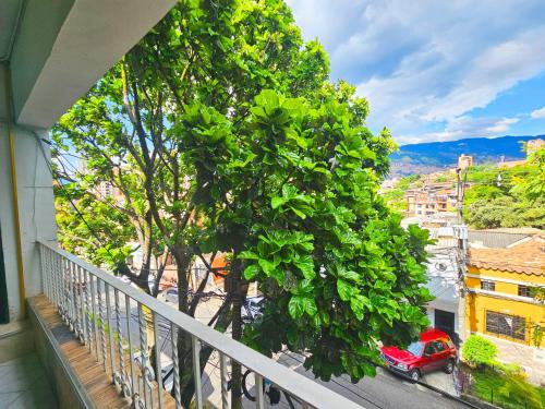 a balcony with a tree and a red car on a street at Apartahotel Casa Blanca in Medellín