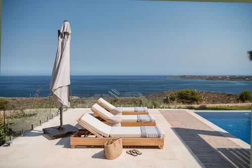 a group of lounge chairs and an umbrella next to a pool at Villa Jamila by Cura Villas Collection in Kalathas
