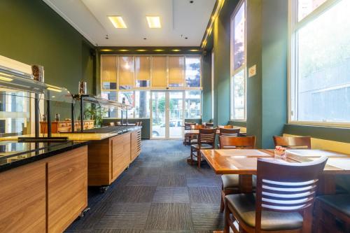 a restaurant with wooden tables and chairs and windows at Higienópolis The Standard Residence in Sao Paulo