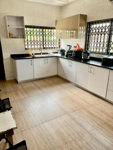 a large kitchen with white cabinets and a wooden floor at Luxe on the lane in Kwedonu