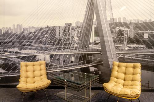 two chairs and a glass table on top of a building at Higienópolis The Standard Residence in Sao Paulo