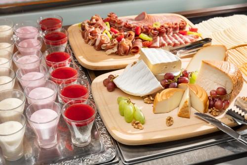 a table with cheese and meats and glasses of wine at Hotel Kálvária in Győr