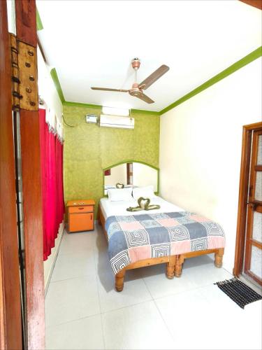 a bedroom with a bed and a ceiling fan at Thilak Home Stay in Hampi