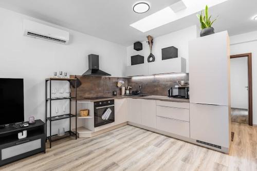 a kitchen with white cabinets and a wooden floor at Modern and Cozy flat with Balcony in Bratislava