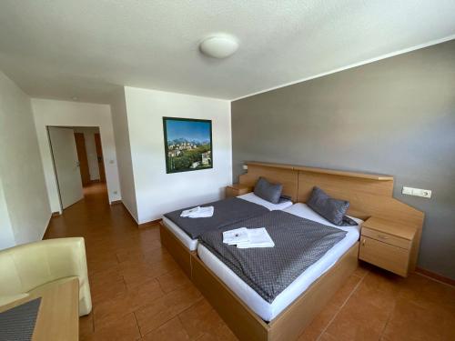 a bedroom with a large bed and a chair at Hotel Bueraner Hof in Melle