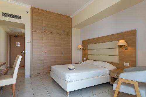 a bedroom with a bed and a desk and a table at Belair Beach Hotel in Ixia