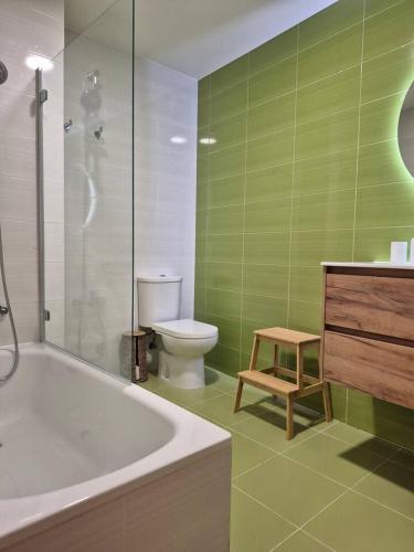 a green bathroom with a toilet and a tub and a stool at Apartamento Mar y Rocas in Malpica