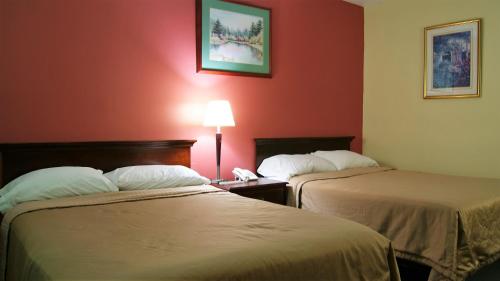 2 Betten in einem Hotelzimmer mit roten Wänden in der Unterkunft Blue Jay Motel in Peterborough