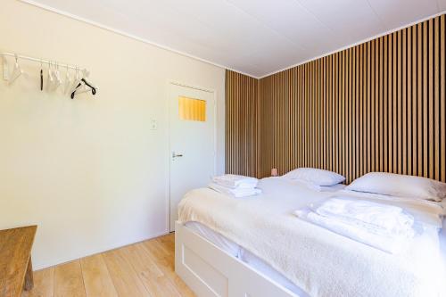 a bedroom with a white bed with a wooden wall at Welcome in - Appartement dichtbij het strand met balkon I Burg van Woelderenlaan 100-23 Vlissingen in Vlissingen