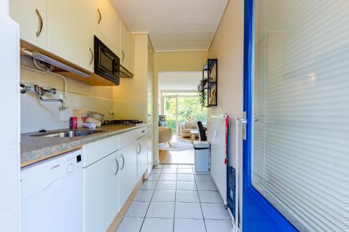 a kitchen with white cabinets and a sink at Welcome in - Appartement dichtbij het strand met balkon I Burg van Woelderenlaan 100-23 Vlissingen in Vlissingen