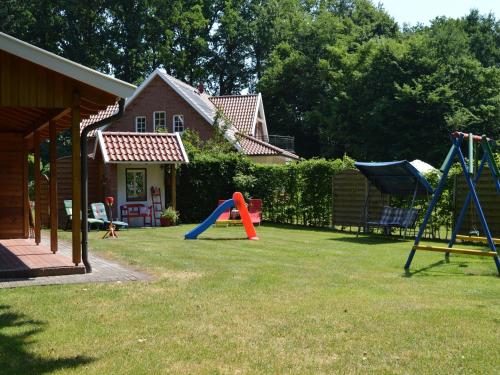 a yard with playground equipment in front of a house at Ferienhaus in Lindern mit Garten & Terrasse in Werlte