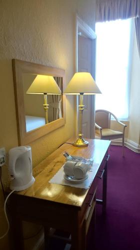 a table with two lamps and a mirror on it at The Belgrave Hotel Tenby in Tenby