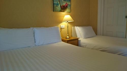 a hotel room with two beds and a lamp at The Belgrave Hotel Tenby in Tenby