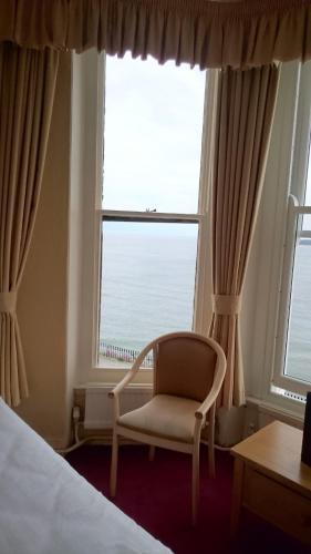 a bedroom with a chair in front of a window at The Belgrave Hotel Tenby in Tenby