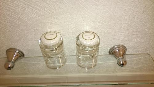 two bottles of water on a glass shelf next to faucets at The Belgrave Hotel Tenby in Tenby