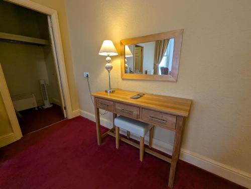 a room with a desk with a mirror and a lamp at The Belgrave Hotel Tenby in Tenby