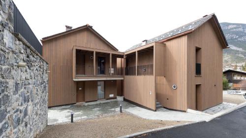 a building with wooden doors and a stone wall at Dosso del Grillo 1A in Valdidentro