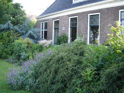 a house with a bunch of bushes in the yard at Waterfront Stelp Farmhouse with Sauna in Molkwerum
