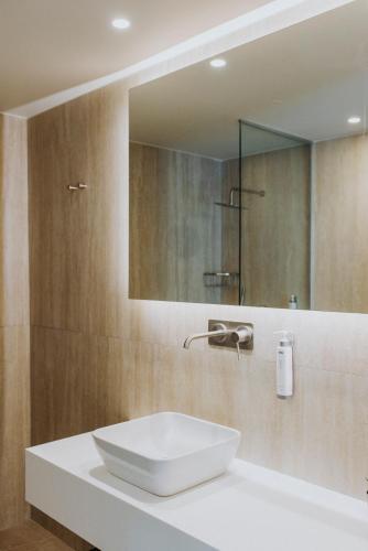 a bathroom with a white sink and a mirror at Volaka Luxury Suites in Kos Town