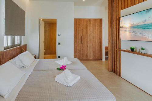 a bedroom with two beds and a tv on the wall at Volaka Luxury Suites in Kos Town