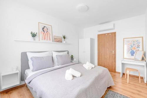 a white bedroom with a large bed with towels on it at Bright Design City Loft with Balcony in Koliba