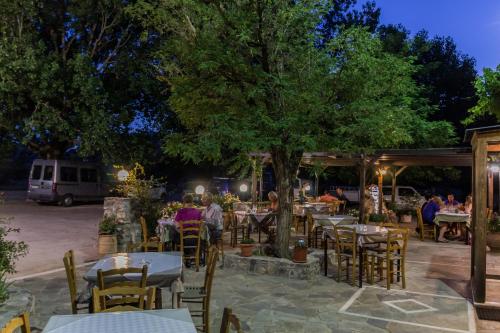 un gruppo di persone seduti ai tavoli sotto un albero di Neos Omalos Hotel a Omalos