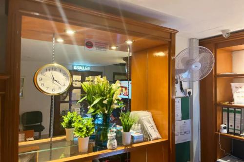 クアラルンプールにあるHotel O Senja Hostel Chinatownの時計が植物と一緒に店の窓に掛けられている