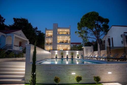 a swimming pool in front of a building at night at Bumblebee apartments & rooms with pool in Novalja