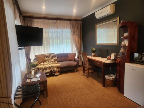 a living room with a couch and a desk at Hillton Manor Guest House in Richards Bay