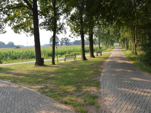 a brick path in a park with a bench and trees at Farmhouse in Haarlo near Lake Hambroek in Haarlo