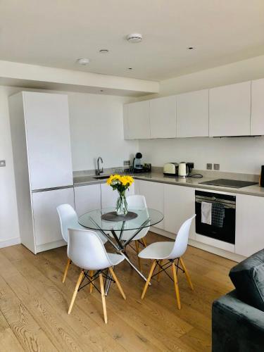 a kitchen with a glass table and white cabinets at 1 bedroom luxury apartment 20 min from centre in London
